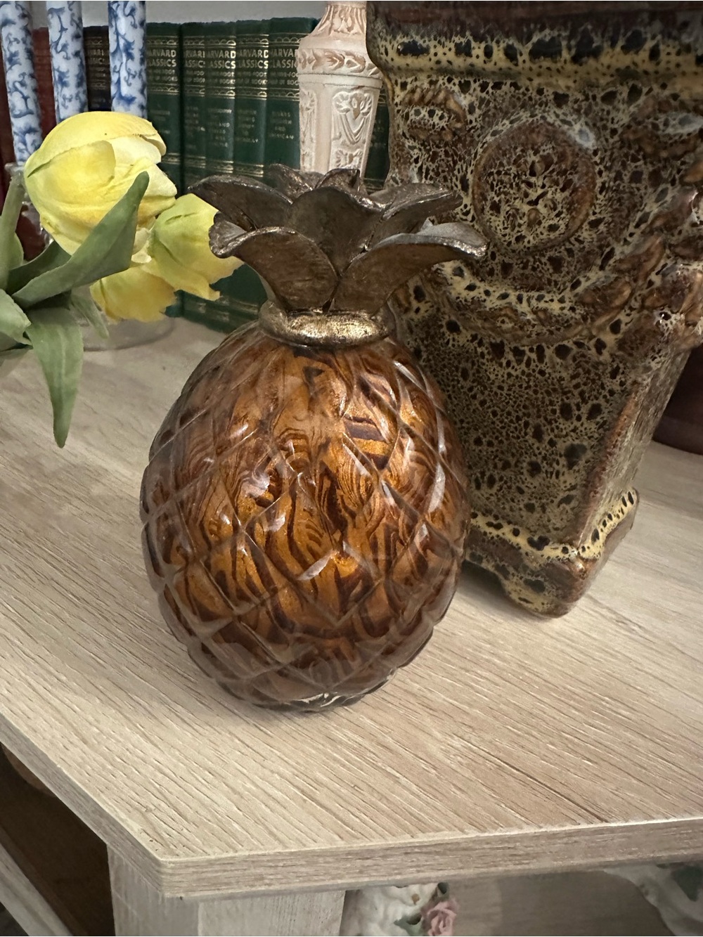 A decorative amber glass pineapple with a metallic leaf top.